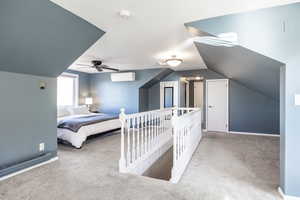 Carpeted bedroom with vaulted ceiling, a wall unit AC, and ceiling fan