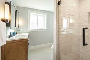 Bathroom with vanity, a tile shower, and toilet