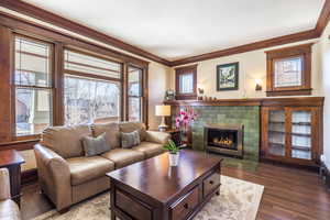 Living room with a tiled fireplace, hardwood / wood-style floors, and crown molding