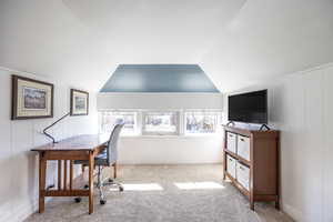 Carpeted home office with vaulted ceiling