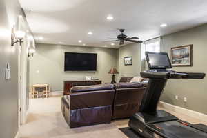 Carpeted living room with ceiling fan and a textured ceiling