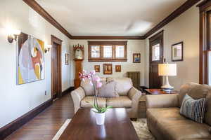 Living room featuring wood-type flooring, radiator, and crown molding