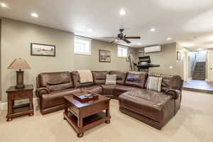 Carpeted living room with a wall unit AC and ceiling fan