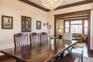 Dining room with ornamental molding, dark hardwood / wood-style floors, and a notable chandelier