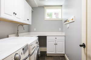 Laundry area featuring cabinets, sink, washing machine and dryer, and dark tile patterned floors