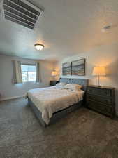 Bedroom featuring a textured ceiling and dark carpet