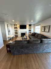 Living room featuring hardwood / wood-style floors, built in features, and a textured ceiling