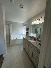 Bathroom featuring tile patterned floors, vanity, separate shower and tub, and a textured ceiling