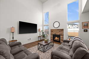 Living room with wood-type flooring, a fireplace, and a high ceiling