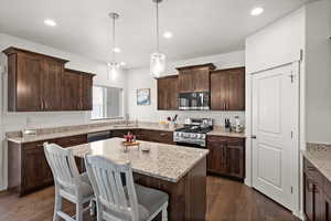 Kitchen with a kitchen island, appliances with stainless steel finishes, sink, hanging light fixtures, and dark brown cabinets