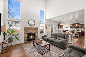 Living room featuring a fireplace, dark hardwood / wood-style flooring, a chandelier, and a towering ceiling