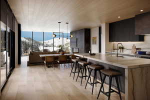 Kitchen with decorative light fixtures, wood ceiling, floor to ceiling windows, a mountain view, and light hardwood / wood-style flooring