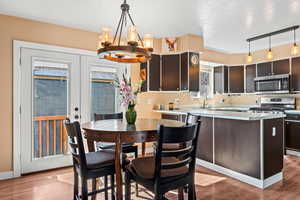 Kitchen featuring stainless steel appliances, french doors, wood finished floors, and light countertops