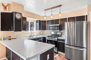 Kitchen featuring stainless steel appliances, light countertops, a sink, and a peninsula