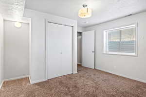 Unfurnished bedroom with carpet, a closet, visible vents, and baseboards