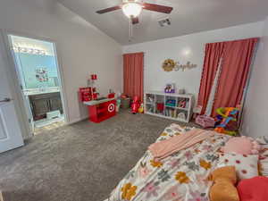 Carpeted bedroom with ensuite bathroom, lofted ceiling, and ceiling fan