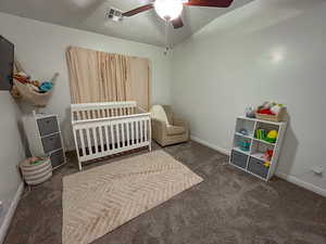 Carpeted bedroom with a crib and ceiling fan