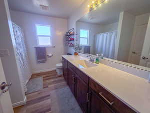 Bathroom with walk in shower, vanity, toilet, and hardwood / wood-style floors