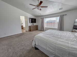 Carpeted bedroom featuring ceiling fan, lofted ceiling, connected bathroom, and a textured ceiling