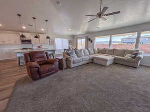 Living room featuring dark hardwood / wood-style flooring, ceiling fan, lofted ceiling, and a textured ceiling