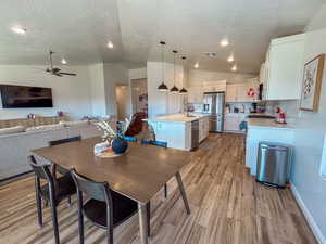 Dining room with lofted ceiling, sink, ceiling fan, light hardwood / wood-style floors, and a textured ceiling