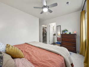 Carpeted bedroom featuring ceiling fan, a spacious closet, and a closet