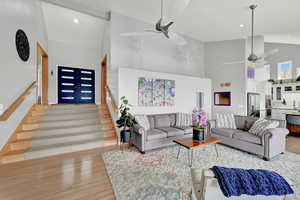 Living room with high vaulted ceiling, light hardwood / wood-style floors, and ceiling fan