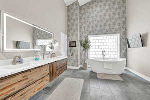 Bathroom with vanity, tile patterned flooring, a bathtub, and high vaulted ceiling