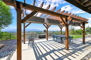 View of patio / terrace with a hot tub, a pergola, and a mountain view