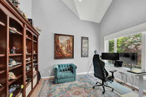 Home office with lofted ceiling and light wood-type flooring