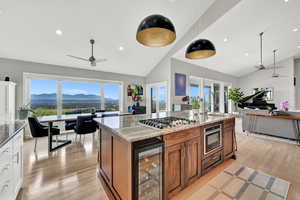 Kitchen with white cabinetry, wine cooler, light stone counters, a mountain view, and stainless steel gas stovetop