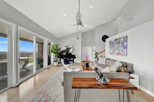 Living room featuring ceiling fan, high vaulted ceiling, and light hardwood / wood-style flooring