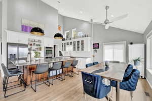 Dining area featuring sink, high vaulted ceiling, light hardwood / wood-style floors, and ceiling fan