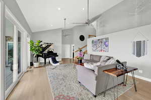 Living room featuring high vaulted ceiling, light hardwood / wood-style floors, and ceiling fan