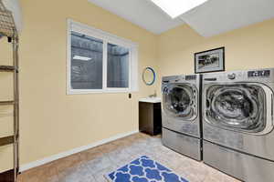 Clothes washing area featuring light tile patterned floors and washer and clothes dryer