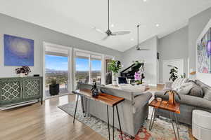 Living room featuring ceiling fan, high vaulted ceiling, and light hardwood / wood-style floors