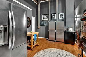 Kitchen featuring stainless steel fridge with ice dispenser, light hardwood / wood-style flooring, and a high ceiling