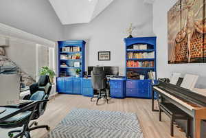 Office space with vaulted ceiling and light wood-type flooring