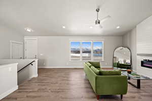 Living room featuring vaulted ceiling, light hardwood / wood-style floors, a large fireplace, and ceiling fan