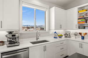 Kitchen featuring white cabinetry, sink, stainless steel dishwasher, a mountain view, and light stone countertops