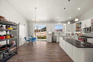 Kitchen featuring decorative light fixtures, white cabinetry, sink, stainless steel appliances, and a barn door