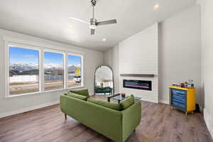 Living room featuring lofted ceiling, ceiling fan, wood-type flooring, a fireplace, and a mountain view