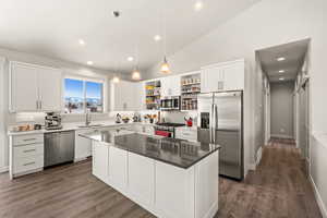 Kitchen featuring stainless steel appliances, a center island, sink, and white cabinets