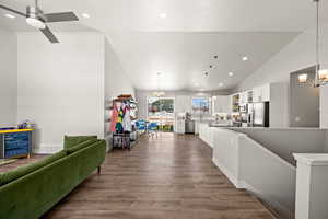 Living room featuring ceiling fan with notable chandelier, vaulted ceiling, hardwood / wood-style floors, and wine cooler