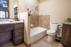 Bathroom with tile patterned floors, vanity, toilet, and a washtub