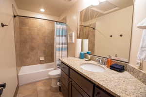 Full bathroom with tile patterned flooring, vanity, shower / tub combo, and toilet