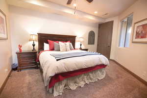 Bedroom with ceiling fan and dark colored carpet