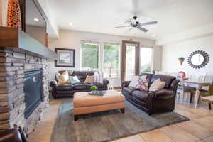 Living room with light tile patterned floors, a fireplace, and ceiling fan