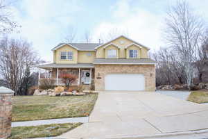 View of front property featuring a garage, a front yard, and covered porch