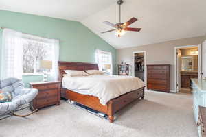 Bedroom featuring ensuite bathroom, a spacious closet, vaulted ceiling, light colored carpet, and a closet